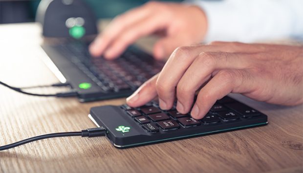 Mannenhanden typen op ergonomisch toetsenbord met muis in achtergrond